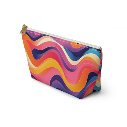 A zippered cosmetic travel bag with a gold zipper, featuring a vibrant wavy pattern in shades of pink, orange, yellow, purple, and blue on white. This T-bottom pouch stands upright and showcases its colorful, modern design.