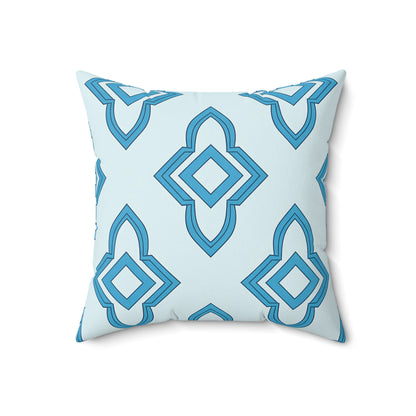A square faux suede pillow with a light blue background features a repeating geometric pattern of layered diamond and pointed shapes in various shades of blue. The pillow is shown facing forward on a white background.