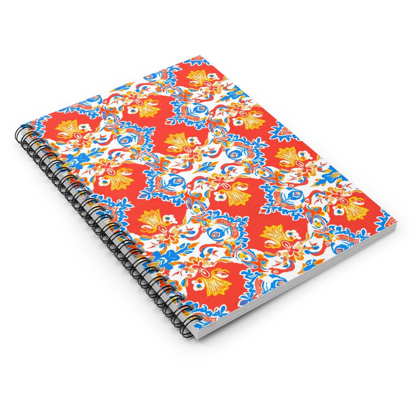 A premium writing journal with a vibrant, African-inspired spiral notebook cover, featuring an ornate red background adorned with blue, yellow, and white floral and leaf patterns in a symmetrical, repeating design. The notebook is shown closed and slightly angled.