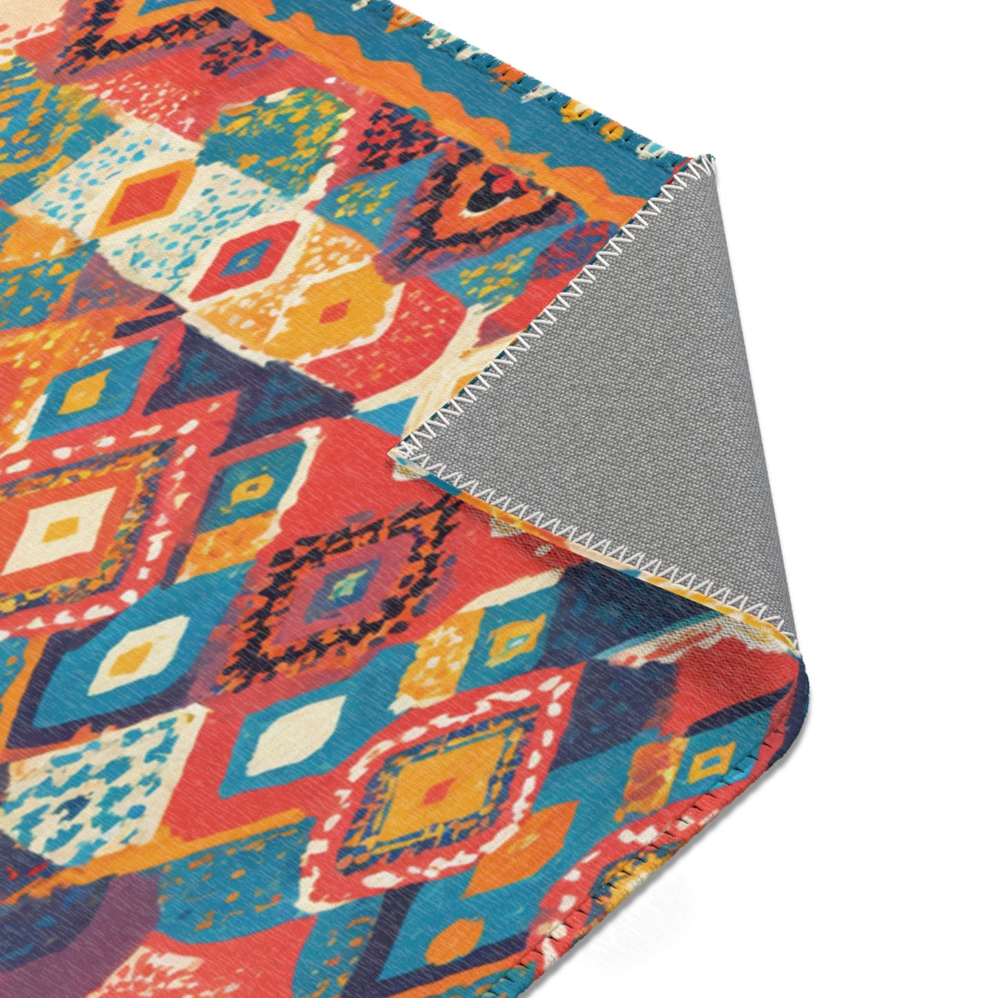 A colorful patterned rug with diamond and geometric shapes in red, blue, yellow, and white adds stylish home decor. Its corner is flipped, revealing a gray underside with white zigzag stitching. The background is white.