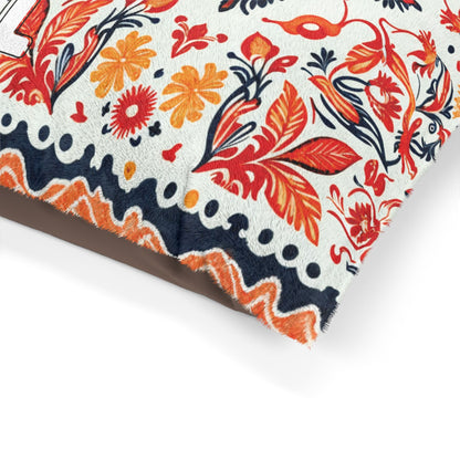A close-up of a fabric with a colorful, African-inspired floral and leaf pattern in shades of orange, red, and navy blue on a white background. The edge features a wavy zigzag border, and the material appears soft and textured, possibly a pillow corner.