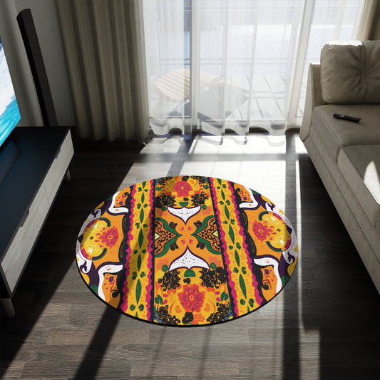 A round, colorful African-inspired rug with floral and geometric patterns in orange, yellow, green, black, and purple sits on a dark wood floor between a beige sofa and a TV. Sunlight filters through sheer curtains, casting bright shadows across the room.