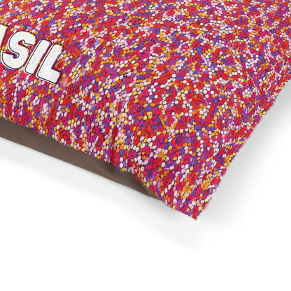 A colorful cushion with a densely packed pattern of small red, pink, orange, and white dots. Part of the word SIL in large, white, embroidered letters is visible in the top left corner. Durable construction ensures lasting appeal on a white background.