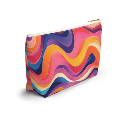 A rectangular T-bottom pouch stands on a white surface. Its exterior features bold, wavy lines in vibrant colors, reminiscent of African-inspired patterns, creating a psychedelic, abstract look. The zipper is white with a gold pull—perfect as a cosmetic travel bag.