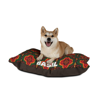 A tan Shiba Inu with pointy ears and a happy expression lies on a personalized pet bed with a dark green and brown floral pattern. BASIL is printed in large white letters, ensuring both style and luxurious comfort. The background is plain white.