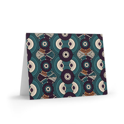 A greeting card with a bold, geometric pattern of overlapping teal, cream, brown, and purple shapes in a symmetrical design. Perfect for lovers of African-inspired greeting cards, the card is blank inside and stands upright on a white surface.