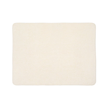 A rectangular, cream-colored bath mat with a soft, plush texture reminiscent of sherpa fleece. The edges are slightly rounded, and the surface appears smooth and uniform. The mat is photographed on a plain white background.
