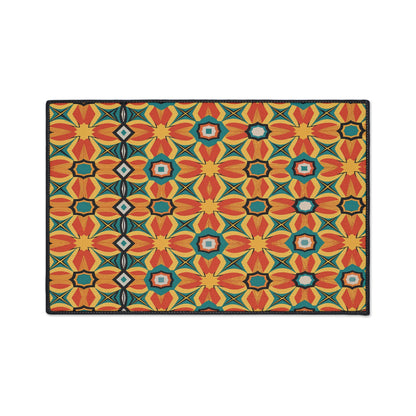A rectangular mat featuring a vibrant, African-inspired geometric pattern with repeating red-orange flowers, yellow diamonds, blue accents, and black outlines on a white background. A vertical black stripe with diamond shapes runs along the left side.