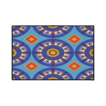 Rectangular mat featuring an African-inspired geometric pattern with blue, purple, yellow, and white sunbursts plus orange diamonds on a light blue background. The vibrant design is eye-catching and includes a non-slip rubber backing for added safety.