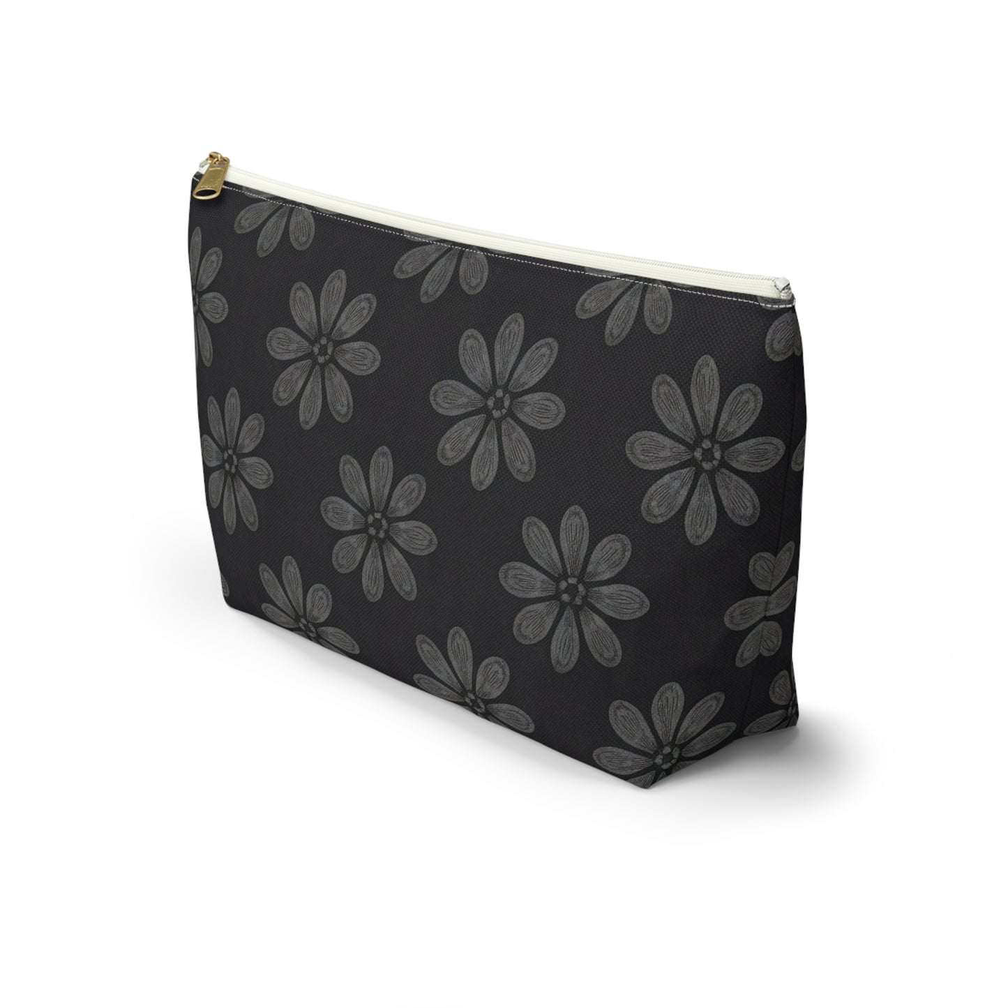 A black zippered T-bottom pouch with a gold zipper and white trim, featuring a repeating pattern of large, gray, hand-drawn daisy-like flowers inspired by African-inspired patterns. The cosmetic travel bag stands upright on a white background.