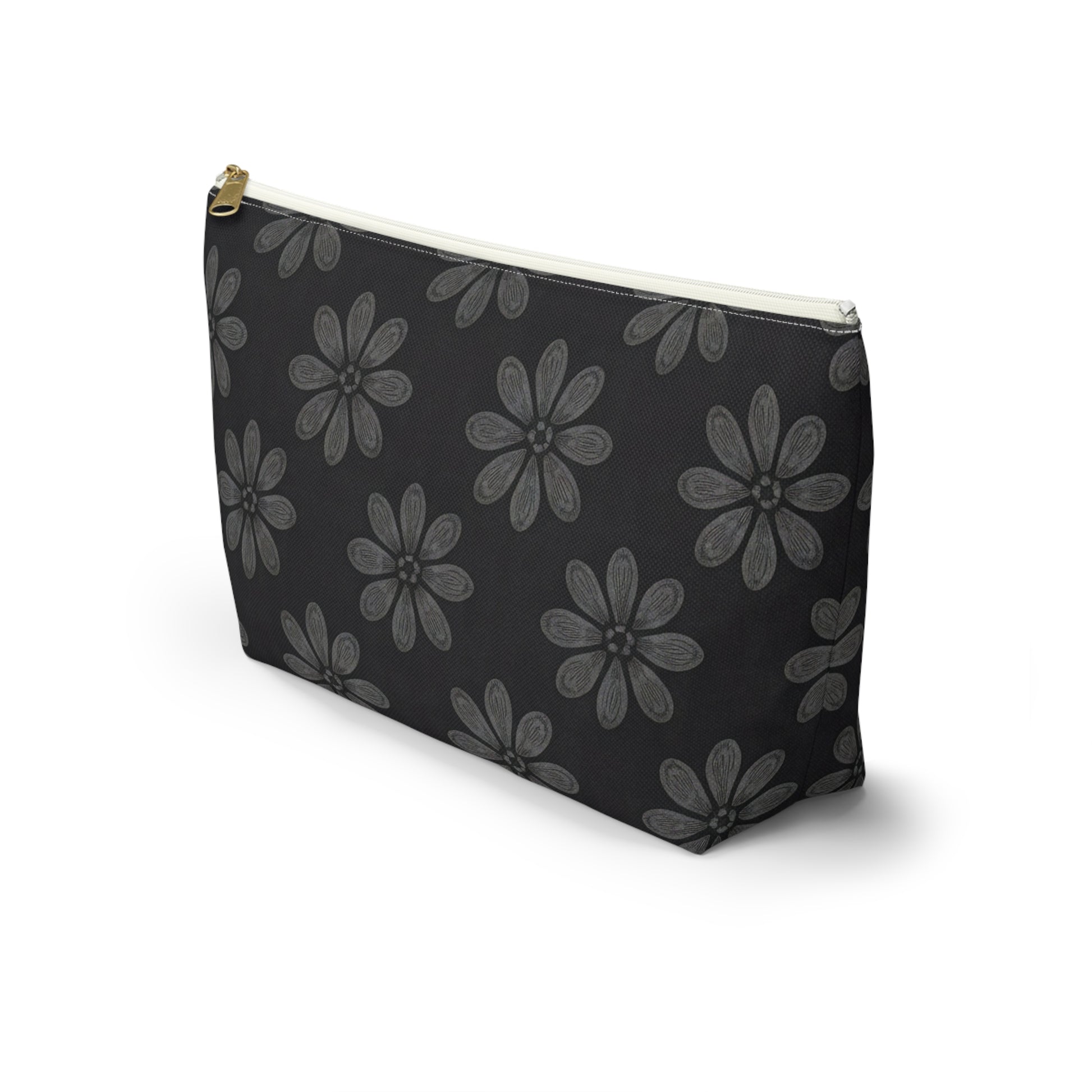 A black zippered T-bottom pouch with a gold zipper and white trim, featuring a repeating pattern of large, gray, hand-drawn daisy-like flowers inspired by African-inspired patterns. The cosmetic travel bag stands upright on a white background.