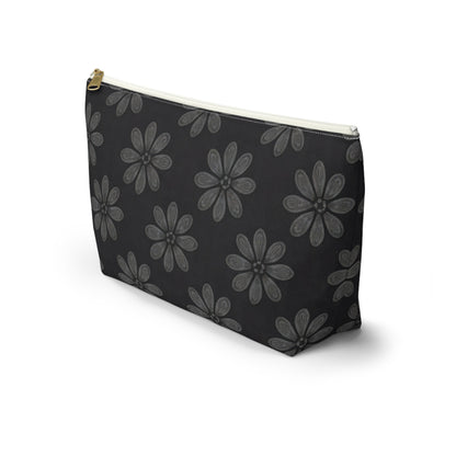 A black zippered T-bottom pouch with a gold zipper and white trim, featuring a repeating pattern of large, gray, hand-drawn daisy-like flowers inspired by African-inspired patterns. The cosmetic travel bag stands upright on a white background.