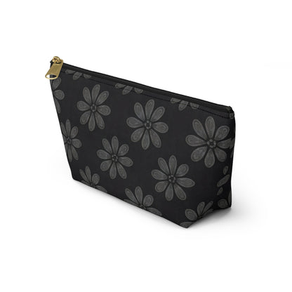 A black T-bottom pouch with a gold zipper pull, decorated with gray, hand-drawn flowers in African-inspired patterns. It stands upright on a white background, angled to show its front and left side—perfect as a stylish cosmetic travel bag.