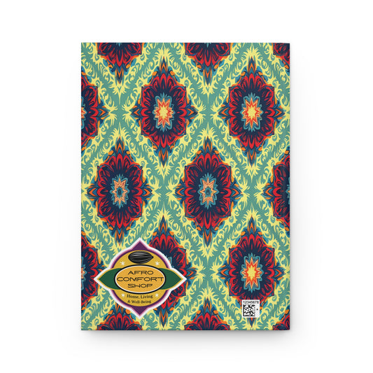 A hardcover monogram journal featuring a vibrant, symmetrical African-inspired pattern in red, blue, and yellow on green. A gold label reads “AFRO COMFORT SHOP,” with a small QR code near it—perfect as a wellness ritual journal.