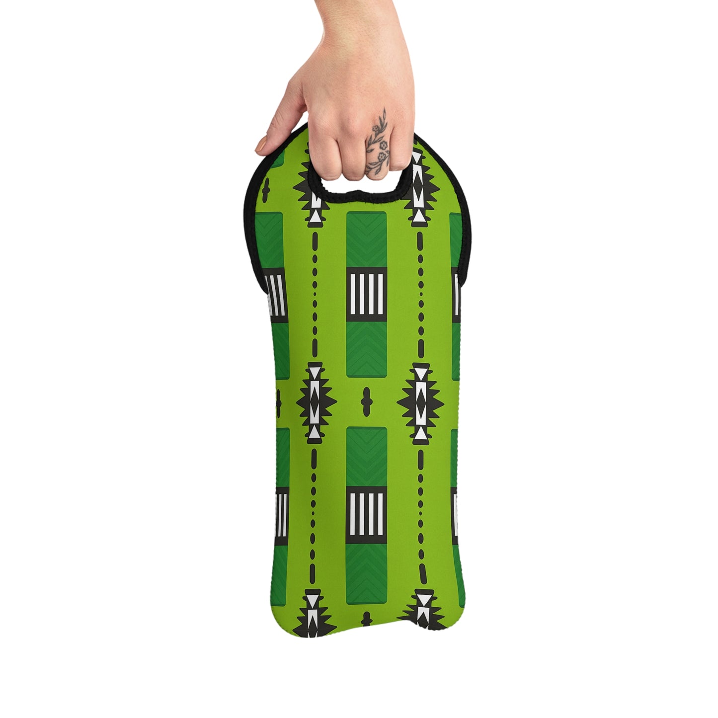 A hand with a floral tattoo holds an insulated wine bag, featuring a bold geometric pattern inspired by African design. This green neoprene wine tote has black trim and a cut-out handle at the top for easy carrying.
