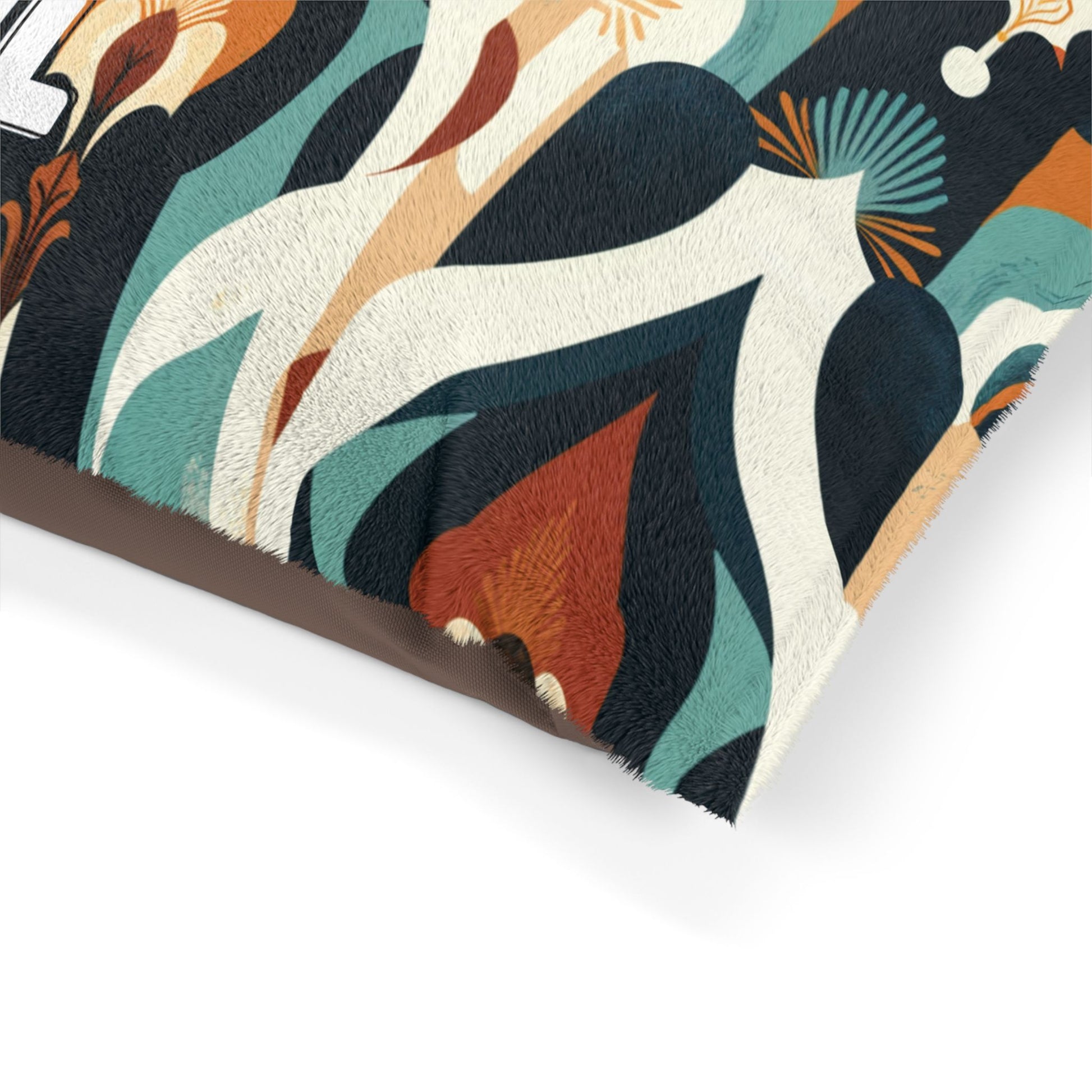 A close-up of a cozy pet bed cushion featuring an abstract, retro-inspired pattern with teal, orange, black, white, and beige organic shapes and lines. The fabric has a textured, fuzzy appearance and only the corner of the cushion is visible.
