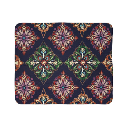 A rectangular sherpa fleece blanket featuring ornate, symmetrical floral motifs in red, green, gold, purple, and white on a dark blue background. The kaleidoscopic designs create cozy home decor with evenly spaced rows.