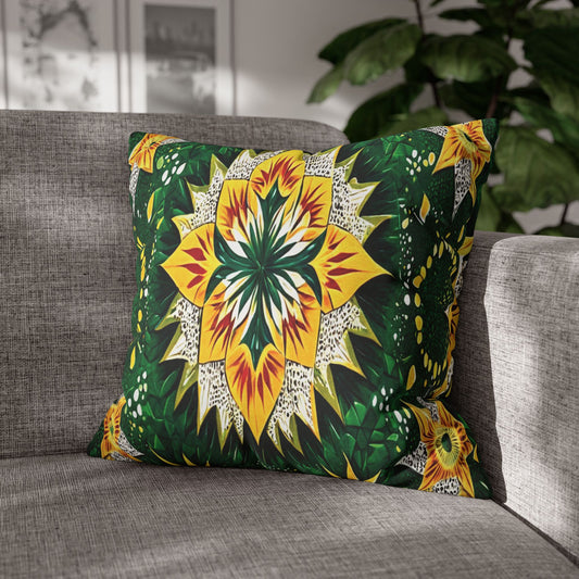 A square pillow with a bold, symmetrical floral design in yellow, green, and white rests on a gray fabric sofa. Sunlight streams in, highlighting its African-inspired pattern. A leafy plant and framed art are blurred in the background.
