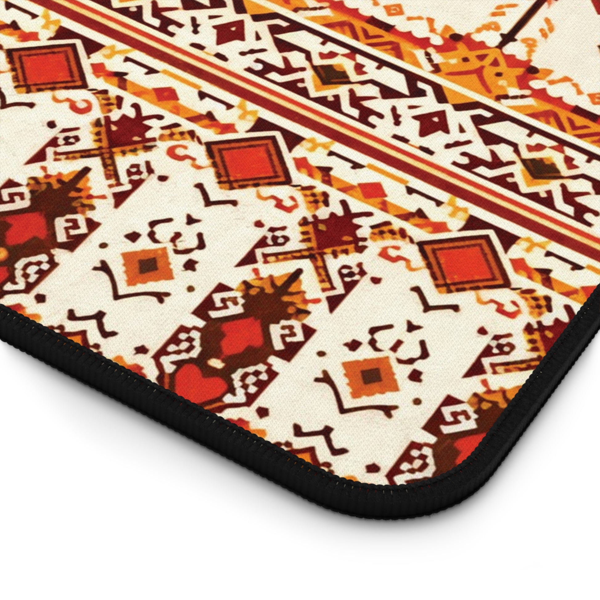 A close-up of a patterned neoprene desk mat with geometric shapes in red, yellow, brown, and orange on a cream background. Diamonds, zigzags, and intricate motifs stand out, bordered by black stitching—perfect as a colorful workspace accessory.