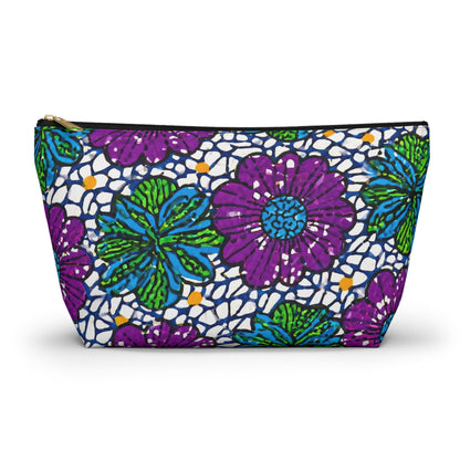 A zippered cosmetic travel bag featuring African-inspired patterns with vibrant purple and green flowers, teal accents, and scattered orange dots on white. The gold zipper and the slightly trapezoidal shape enhance this chic T-bottom pouch.