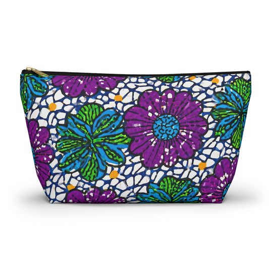 A zippered cosmetic travel bag featuring African-inspired patterns with vibrant purple and green flowers, teal accents, and scattered orange dots on white. The gold zipper and the slightly trapezoidal shape enhance this chic T-bottom pouch.