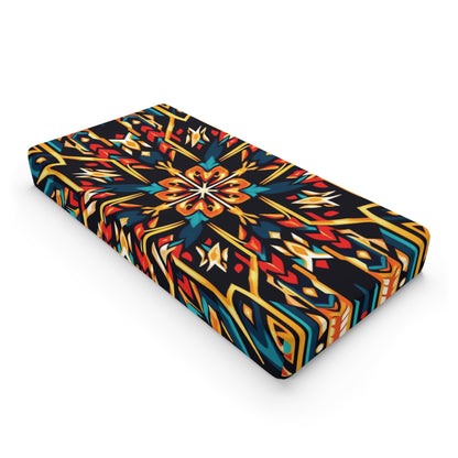 A rectangular mattress features a vibrant geometric and floral pattern in red, yellow, blue, and white on black. The lively, decorative look is perfect for African-inspired changing pad covers or custom changing pad covers.