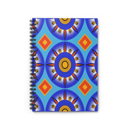 A spiral-bound notebook with a vibrant, African-inspired cover featuring blue circular sunburst shapes, yellow centers, and white rays, accented by orange and red diamonds—all set against a bright blue background for a premium writing experience.