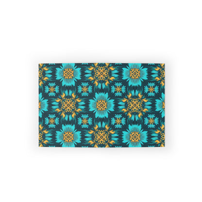 Rectangular mat with a vibrant, symmetrical floral pattern showcasing culturally inspired designs. Teal blue and yellow flowers create a lively geometric motif on a dark background. The mat is centered on a white surface.