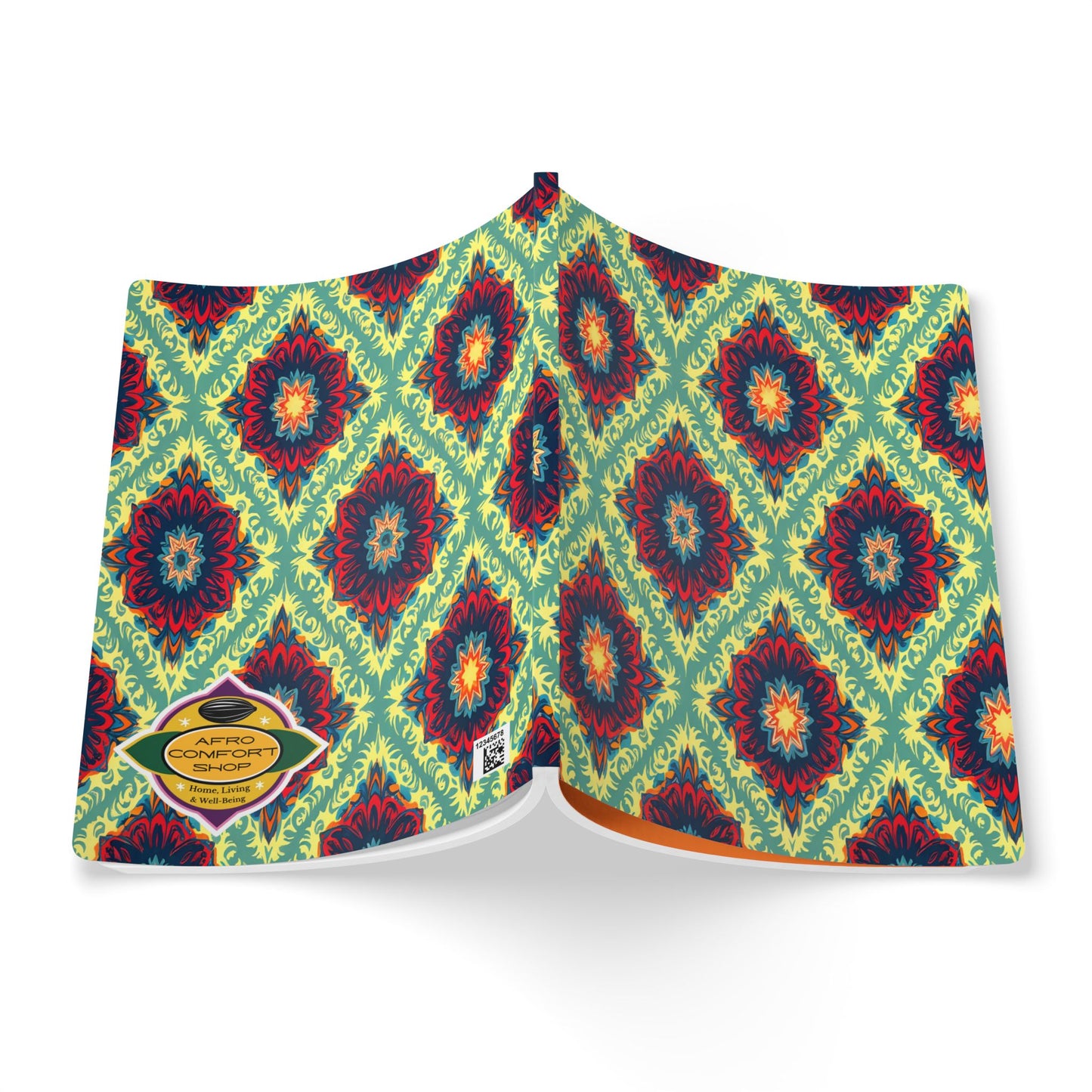 An open African-inspired journal displays a vibrant cover with a repeating geometric floral pattern in red, blue, and yellow on a green background. A yellow label reads AFRO COMFORT: THE COLLECTION, and the pages are slightly fanned out.