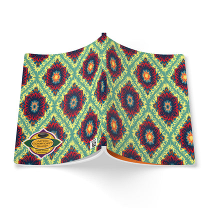 An open African-inspired journal displays a vibrant cover with a repeating geometric floral pattern in red, blue, and yellow on a green background. A yellow label reads AFRO COMFORT: THE COLLECTION, and the pages are slightly fanned out.