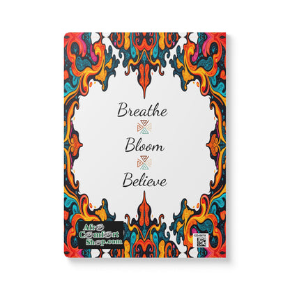 Notebook cover with ornate, colorful, swirling patterns framing a white center. In the center, black script reads “Breathe Bloom Believe.” Perfect as an African-inspired journal for daily journaling. Alfa Comfort Shop logo and QR code included.