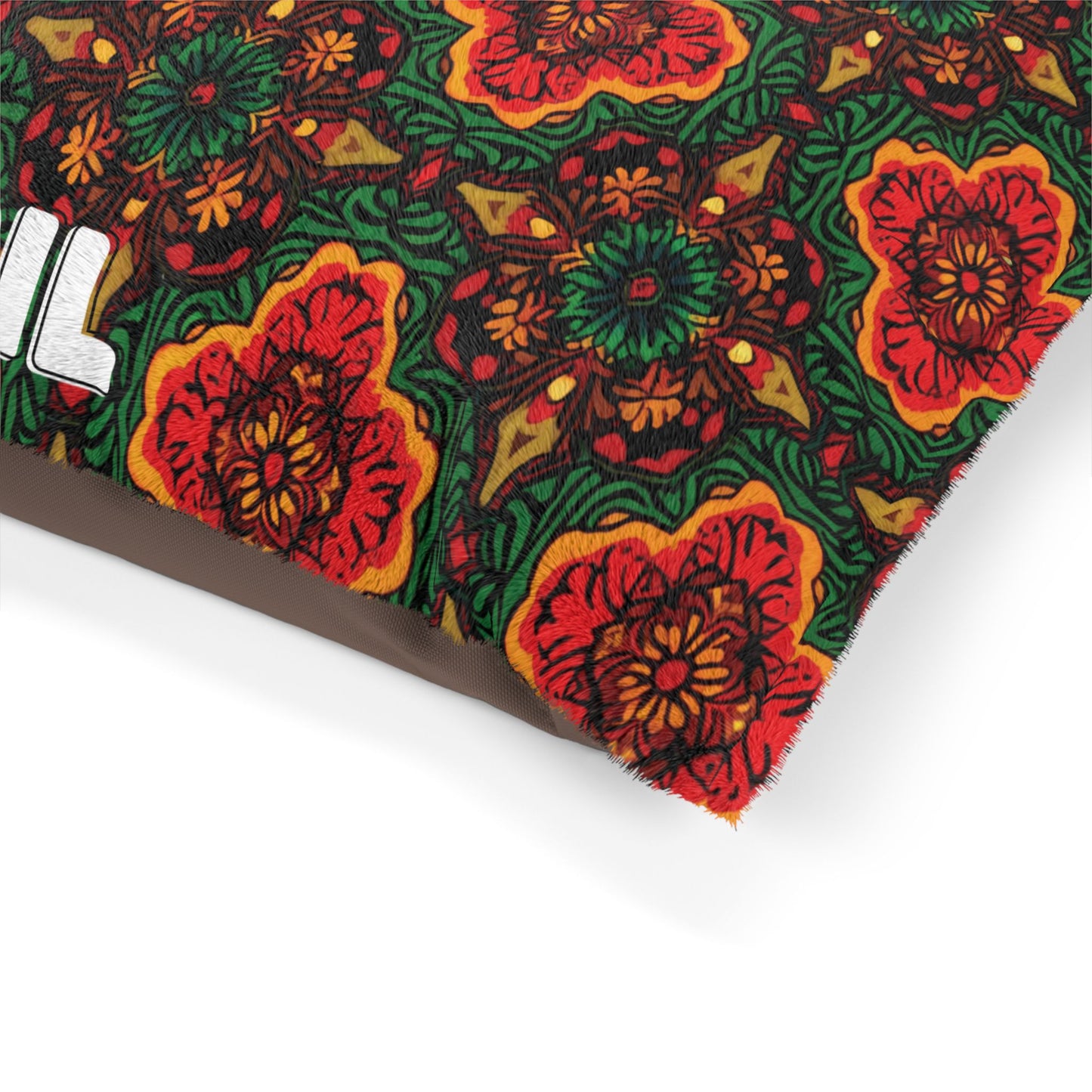 A close-up of a pillow corner with a vibrant, African-inspired floral pattern. The design includes large red and orange flowers with green leaves set against a dark background. Part of a white, bold letter appears on the left side.