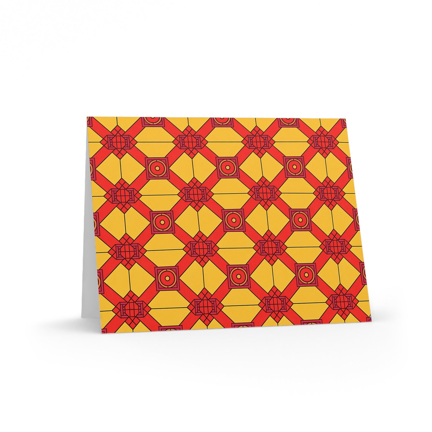 A premium stationery greeting card stands upright, featuring a geometric pattern in yellow and red. Its repeating diamond and square shapes evoke a culturally inspired design, set against a yellow background and pictured on a white surface.