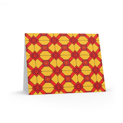 A premium stationery greeting card stands upright, featuring a geometric pattern in yellow and red. Its repeating diamond and square shapes evoke a culturally inspired design, set against a yellow background and pictured on a white surface.