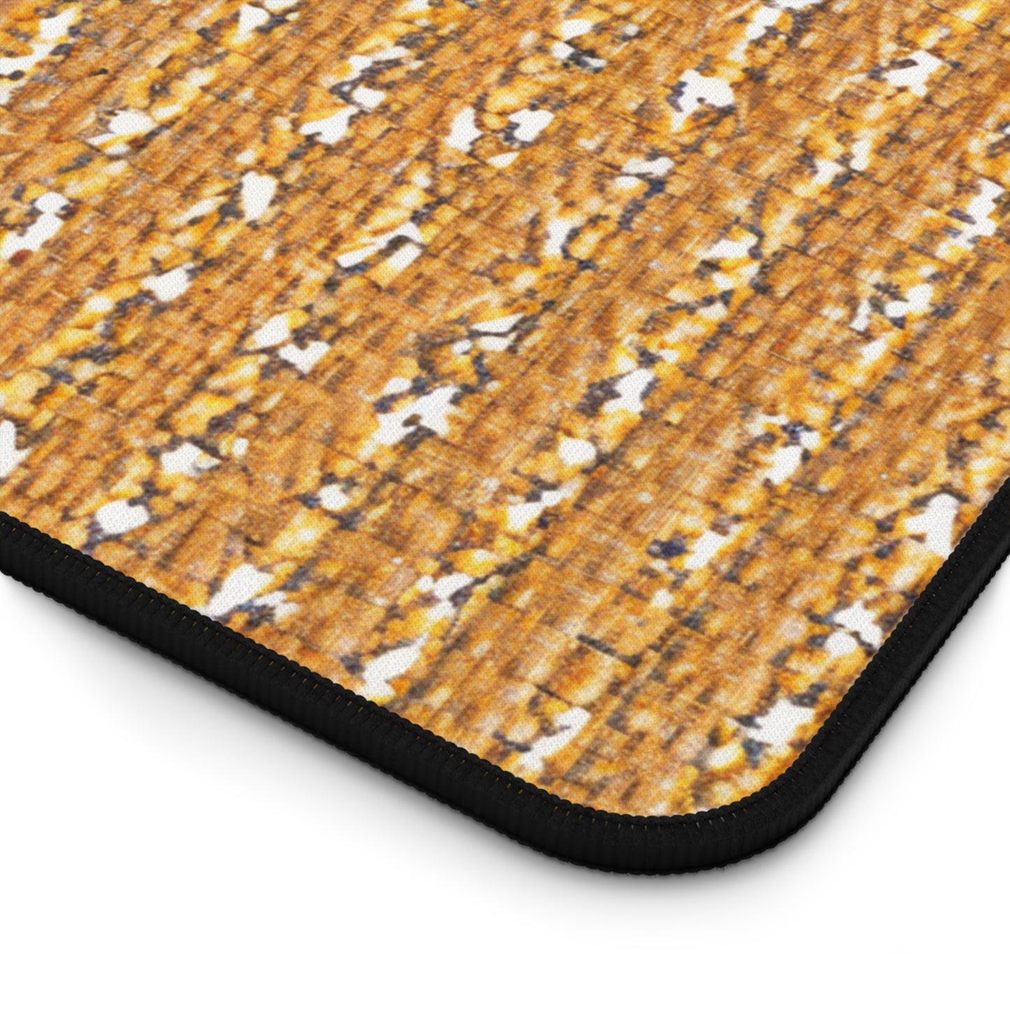 Close-up of a rectangular Neoprene desk mat with a textured pattern resembling brown and orange wood shavings or bark, featuring scattered white patches. The mat has a black, rounded trim along its edge—perfect as a colorful workspace accessory.