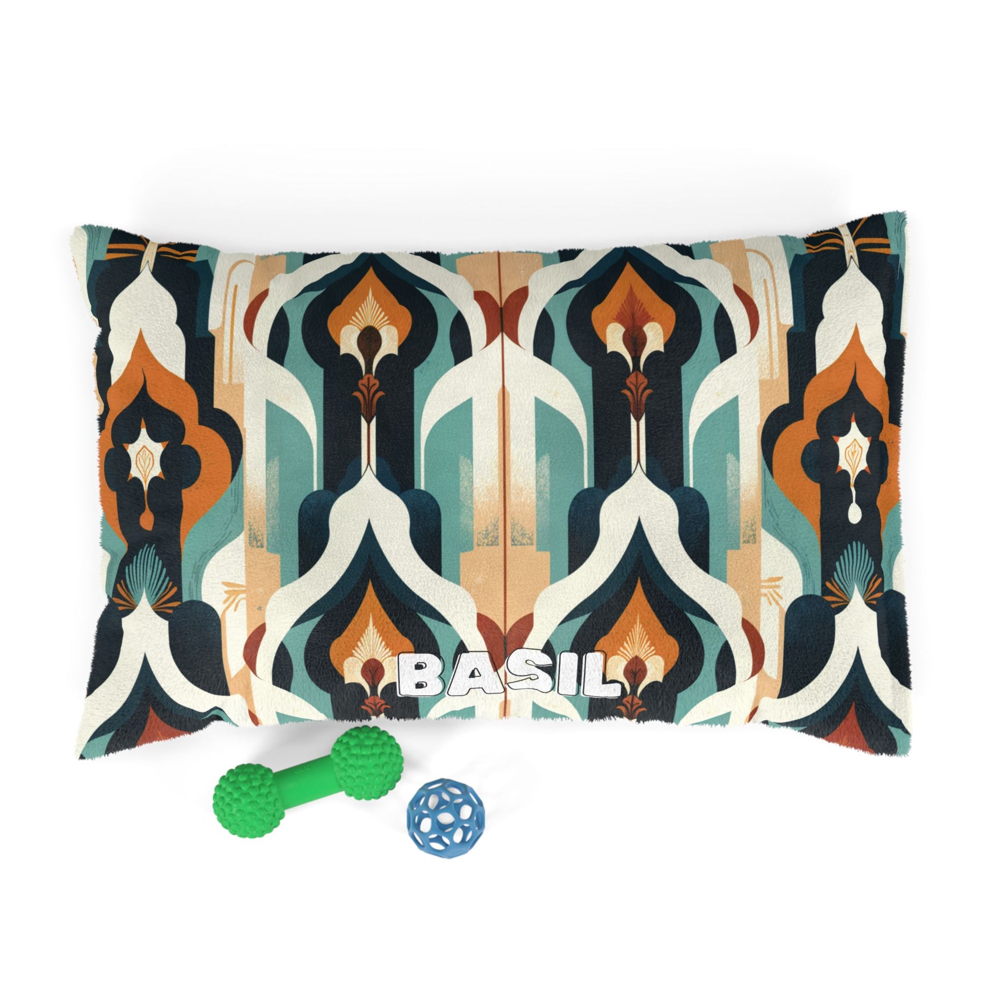 A rectangular pillow with an abstract geometric pattern in teal, navy, orange, beige, and white features BASIL in bold white letters. In front are a green bone and blue ball—this cozy pet bed boasts durable construction for lasting comfort.