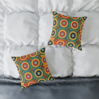 Two square vibrant throw pillows with colorful starburst and geometric patterns in red, yellow, green, and blue rest on a white, tufted bedspread. This colorful home decor is accented by a gray edge or blanket at the foot of the bed.