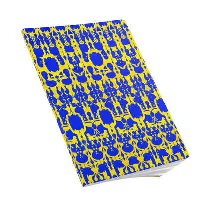 A closed African-inspired journal with a blue and yellow ornate, abstract pattern on the cover. Interlocking shapes and symmetrical motifs create a vibrant, eye-catching look. The creative journal is positioned at an angle on a white background.