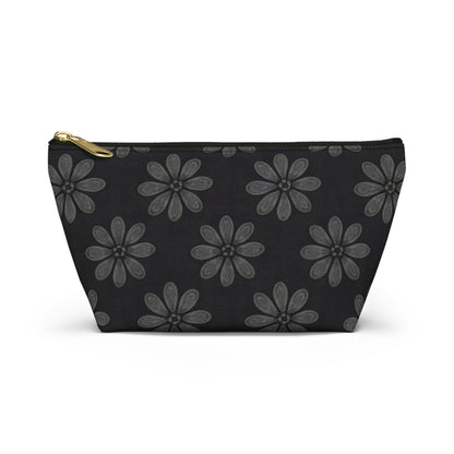 A black cosmetic travel bag with a gold zipper, featuring African-inspired patterns of large, gray, six-petaled flowers evenly spaced across the solid black T-bottom pouch. Displayed upright against a white backdrop.