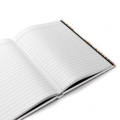 An African-inspired notebook with a vibrant tribal pattern lies open on a white surface, its hardcover angled slightly to the right. Colorful inner edges peek out, and the blank wide-ruled pages are ready for writing.