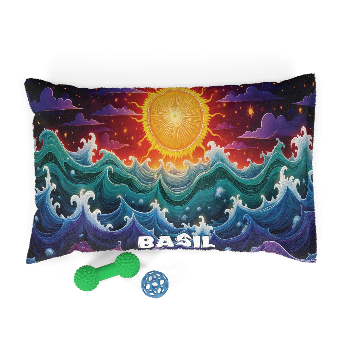 Rectangular pillow with colorful, swirling ocean waves and a radiant yellow sun above. The name BASIL is printed at the bottom, making it a personalized pet bed. Two dog toys—a green bone-shaped toy and a blue ball—sit in front on a white background.