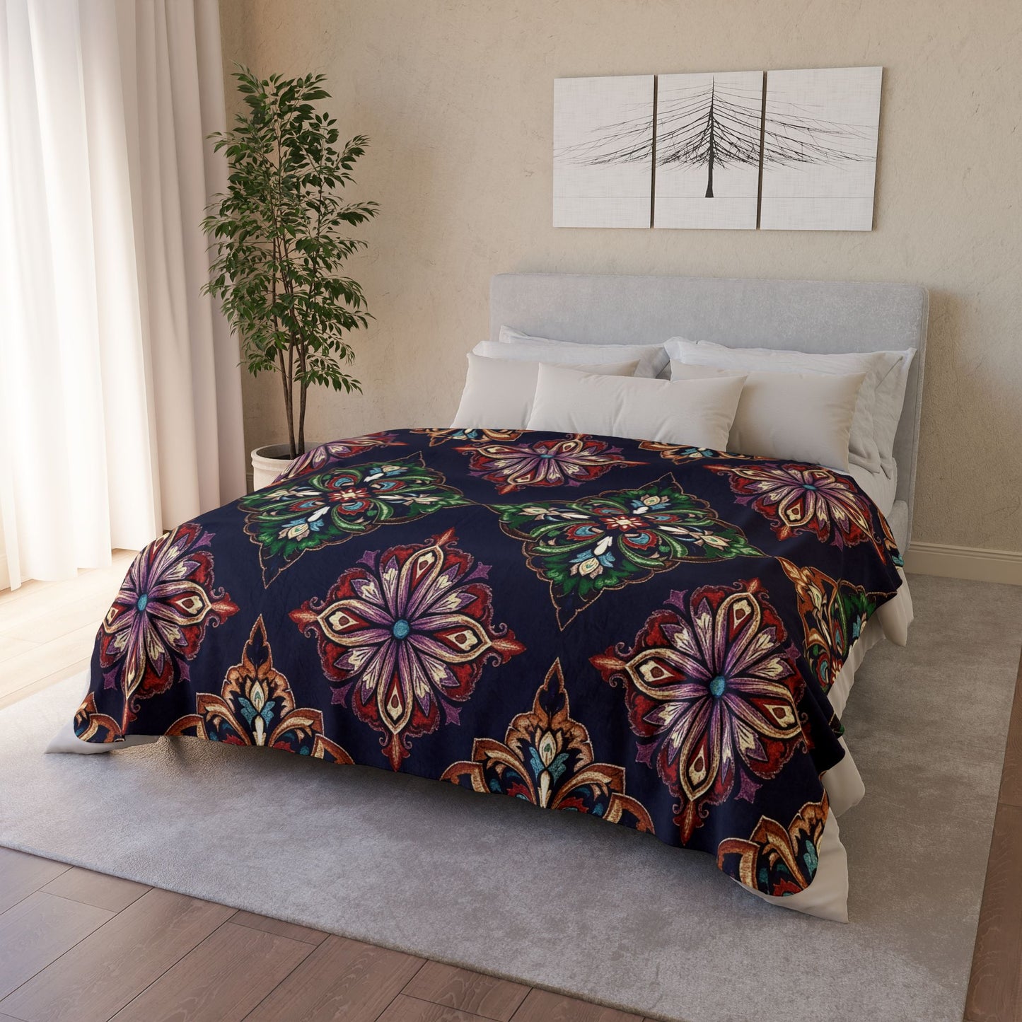 A bed with white pillows and a gray upholstered headboard is covered by a dark quilt with large, ornate, multicolored floral patterns. African-inspired fleece blankets add cozy home decor, while two abstract artworks hang above the bed.