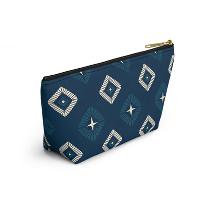 A blue cosmetic travel bag with a gold zipper, featuring African-inspired patterns in a geometric diamond design of white and navy. The T-bottom pouch stands upright, displaying radiating lines and star shapes at each center against a white background.