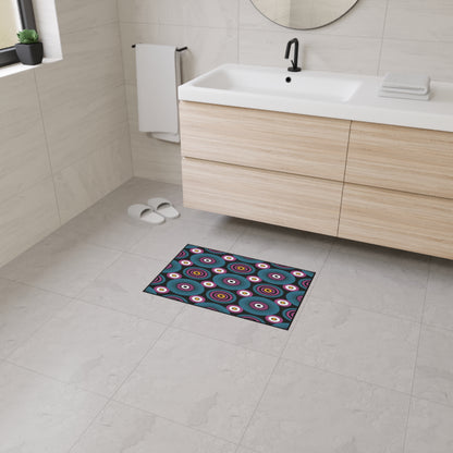 Modern bathroom with light gray tile floor and walls, floating wooden vanity with white sink, black faucet, round mirror, folded towels, a towel on a wall rack, white slippers, and an African-inspired custom floor mat with geometric circular patterns and non-slip rubber backing.