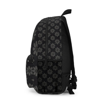 A black boho chic rucksack with a side view, featuring a gray and white daisy floral pattern. It offers a front zippered pocket, side mesh pocket, adjustable straps, and top handle. Main compartment zipper and stitching stand out against the black fabric.