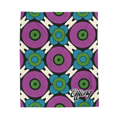 A vibrant, geometric African-inspired blanket featuring large purple circles with blue and green floral shapes on a cream background. Black diagonal lines add contrast, while Effiong appears in bold script—perfect as a personalized velveteen blanket.
