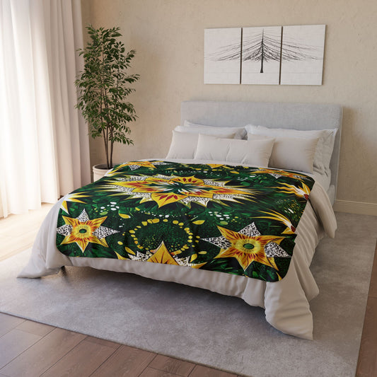 A neatly made bed with light grey bedding features a vibrant, African-inspired fleece blanket with green, yellow, and white star patterns. The room includes a potted plant, light rug, white curtains, and black-and-white wall art above the bed.