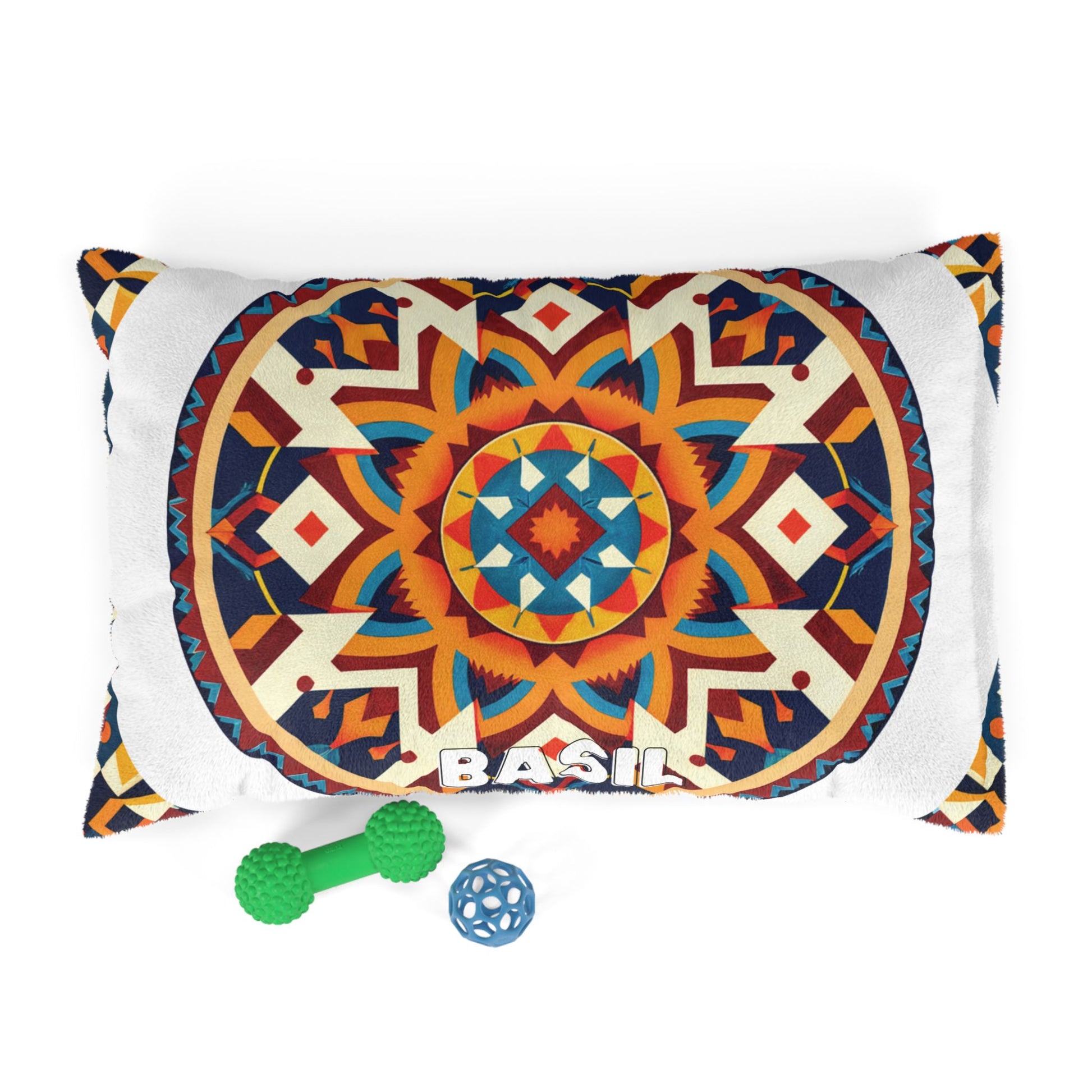 A rectangular pillow with a colorful mandala pattern and the name BASIL at the bottom offers luxurious comfort. Two dog toys—a green bone-shaped toy and a blue textured ball—are placed next to this personalized pet bed on a white background.
