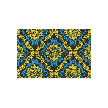 A rectangular outdoor patio rug featuring a repeating geometric pattern with yellow and blue floral motifs on black, arranged in diamond shapes. This African-inspired outdoor rug offers bold, vibrant style and is crafted from weather-resistant polyester chenille.