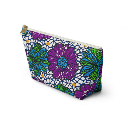 A zippered T-bottom pouch with a bold floral pattern in purple, blue, and green, outlined in black on white. This cosmetic travel bag stands upright and features African-inspired patterns with prominent flowers and a lace-like background.